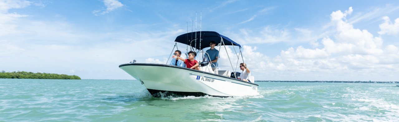 Father and son with friends exploring in a fishing boat.